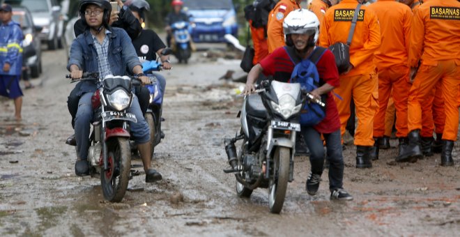 Residentes locales con sus scooters en una carretera embarrada después de un tsunami en el Estrecho de Sunda en Pandeglang, Banten, Indonesia.- EFE/EPA/ADI WEDA