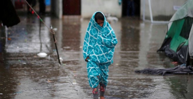 Una niña centroamericana que viaja en una caravana de migrantes, envuelta en una toalla para protegerse de la lluvia en un refugio de Tijuana. / REUTERS - MOHAMMED SALEM