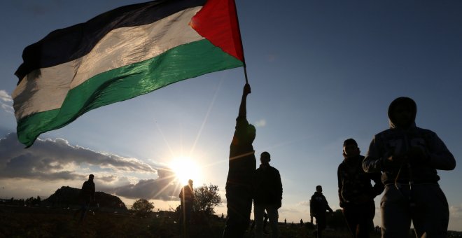 Manifestantes despliegan una bandera de Palestina durante una protesta junto a la frontera en Gaza. - REUTERS