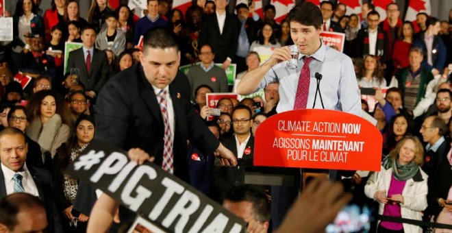 Justin Trudeau observa cómo un miembro de su equipo de seguridad reduce a un asistente durante un reciente mitin en Toronto. (REUTERS)