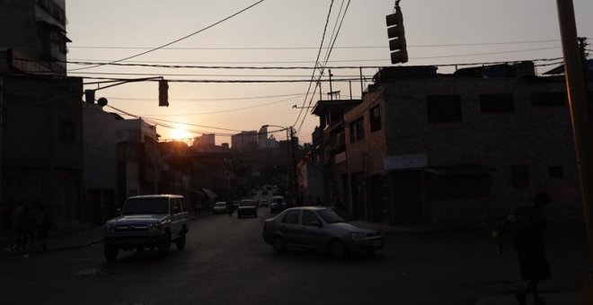 Vehículos transitan por una calle sin alumbrado público por la falta de fluido eléctrico en la zona en Caracas. /RAYNER PEÑA (EFE)