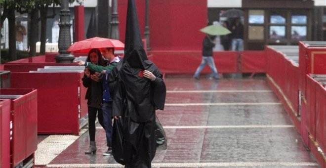 Imagen de archivo de un nazareno del Sepulcro que camina bajo la lluvia. SALAS / EFE