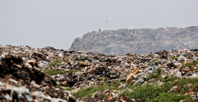 Un hombre recolecta materiales reciclables a medida que el humo se acumula en un vertedero en llamas con motivo del Día de la Tierra, en Calcuta. / Reuters