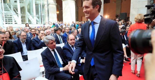 02/05/2019.- El presidente del PP, Pablo Casado (d), pasa por delante del expresidente de la Comunidad de Madrid, Angel Garrido (sentado-2i), a su llegada a los actos conmemorativos de la festividad del Dos de Mayo, Día de la Comunidad de Madrid, este jue