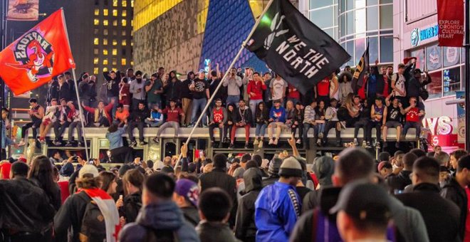 14/06/2019.- Aficionados de los Raptors de Toronto celebran la victoria de su equipo en Toronto, Canadá, este jueves 13. Los Raptors de Toronto, favorecidos con las bajas del alero Kevin Durant y del escolta Klay Thompson, derrotaron a domicilio esta noch