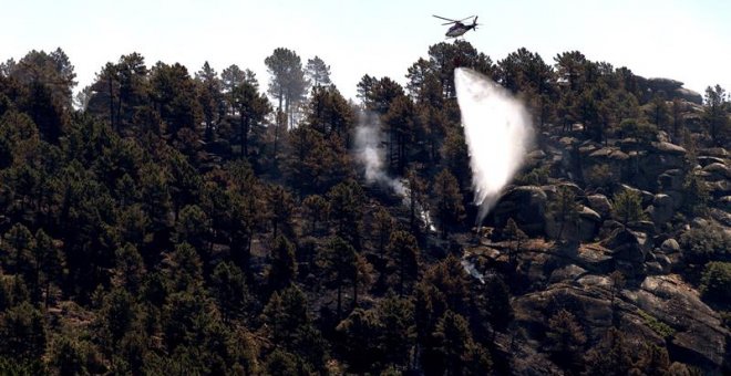 Un helicóptero trabajando en las labores de extinción del incendio en el término de El Arenal (Ávila), la Junta de Castilla y León ha rebajado el nivel de peligrosidad de los incendios que aún permanecen activos en los municipios abulenses de El Arenal, G