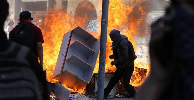 22-10-19 / Varios encapuchados montan barricadas frente a la policía tras manifestarse este martes en el centro de Santiago (Chile).  EFE/Elvis González