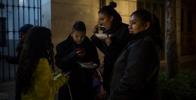 Una madre, solicitante de asilo colombiana, cena gracias a la ayuda de la Red de Solidad Popular, junto a sus tres hijos menores, en la puerta del Samur Social de Madrid-. JAIRO VARGAS