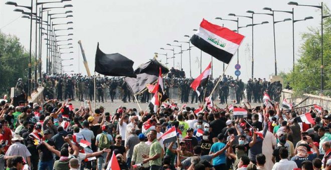 Manifestantes iraquíes portan banderas nacionales mientras gritan consignas, este viernes durante una manifestación cerca de la sede central del gobierno iraquí, en el centro de Bagdad. (AHMED JALIL |EFE)