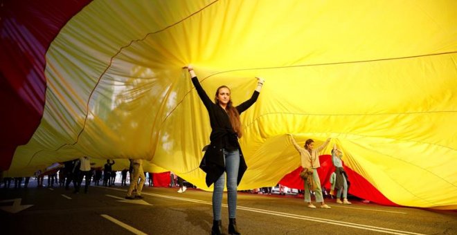 Decenas de personas sostienen la bandera de España de 1.000 metros cuadrados -50 de largo por 20 de ancho y con unos 130 kilos de peso, durante la concentración convocada por Vox para defender la "unidad de España, el orden constitucional y la convivencia