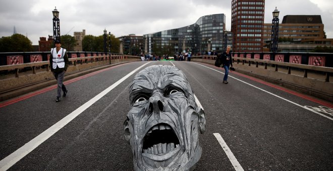 Los activistas ecologistas dejan en mitad del Puente Lambeth (Londres) la escultura de un rostro con cara de dolor. REUTERS