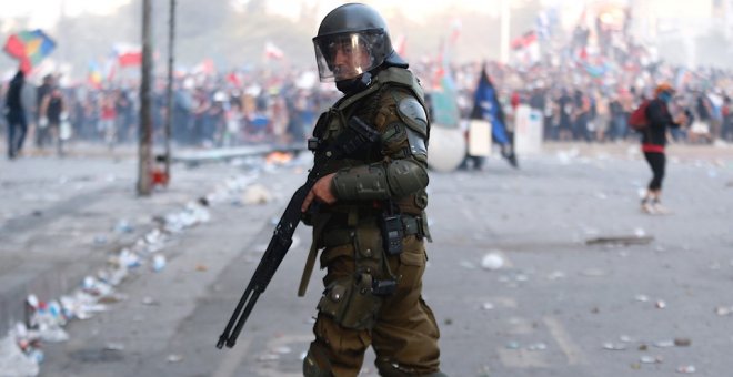 Un miembro de los Carabineros, el cuerpo policial de Chile, frente a los manifestantes en la céntrica Plaza Italia de Santiago. EFE/Alberto Valdés