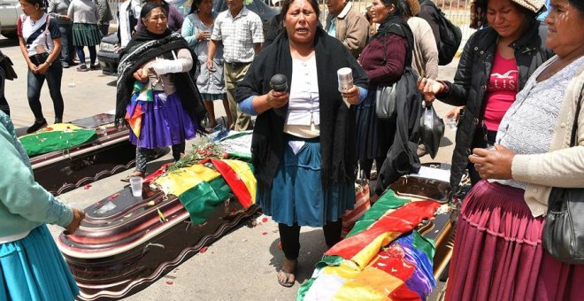 16/11/2019.- Un grupo de mujeres realiza una ceremonia ante los féretros de varios de los fallecidos tras los disturbios de ayer con las fuerzas del orden, frente al Instituto de Investigaciones Forenses este sábado, en Cochabamba (Bolivia). El número de