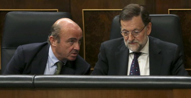 El equipo económico de Rajoy, con Luis de Guindos a la cabeza, siempre sostuvo que el rescate no iba a costarle dinero al Estado. En la imagen, el entonces ministro de Economía con el presidente del Gobierno en el Congreso de los Diputados. EFE