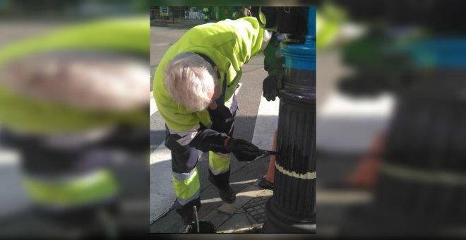 Imagen de un trabajador pintando de negro la bandera arcoíris de un semáforo de Granada.