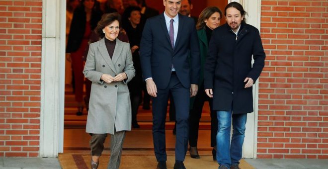 El primer ministro, Pedro Sánchez (C), camina junto a la vicepresidenta primera y ministra de Presidencia y Realciones con las Cortes, Carmen Calvo (i), y el vicepresidente de Derechos Sociales y Agenda 2030, Pablo Iglesias (d), momentos antes de posar pa