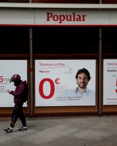 Un hombre con un casco de motorista pasa por delante de una sucursal del Banco Popular eb Madrid. REUTERS/Susana Vera