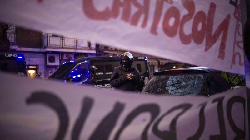 Un policía antidisturbios delante de las pancartas contra el desahucio de José Manuel y María, de 80 años, en Carabanchel, Madrid.