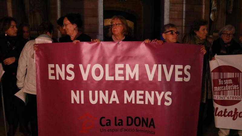 Diverses dones subjectant una pancarta a la concentració convocada a la plaça Sant Jaume de Barcelona.