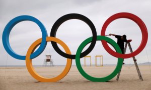 Un hombre pinta los anillos olímpicos en la playa de Copacabana para ultimar los preparativos de los juegos olímpicos de Río de Janeiro/REUTERS