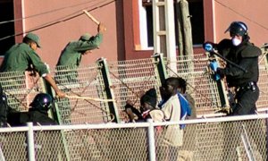 Agentes de la Guardia Civil y las fuerzas auxiliares marroquíes tratan de impedir que que varias personas migrantes salten la valla de Melilla.- CAMINANDO FRONTERAS