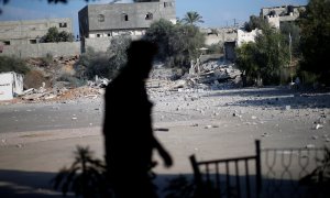 Un miembro de las fuerzas de seguridad palestinas de Hamas camina frente a las ruinas de un edificio tras un ataque aéreo israelí. / REUTERS - MOHAMMED SALEM