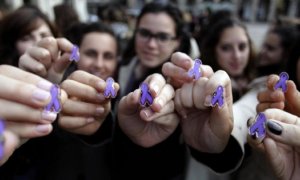 Un grupo de jóvenes muestran pines con lazos morados contra la violencia machista. EFE/Archivo