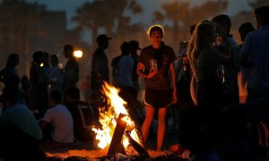 Una joven observa las llamas de la hoguera que ha encendido junto a un grupo de amigos para celebrar la Noche de San Juan | EFE