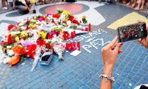 16/08/2019 - Una turista fotografía los ramos de flores y objetos de todo tipo depositados en el mural de Miro de La Rambla de Barcelona en recuerdo de los atentados en La Rambla y Cambrils. - EFE/Alejandro García