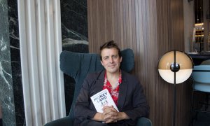 El periodista Oliver Bullough, autor de 'Moneyland', posa con su libro en un hotel de Madrid. (PRINCIPAL DE LOS LIBROS)