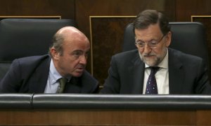 El equipo económico de Rajoy, con Luis de Guindos a la cabeza, siempre sostuvo que el rescate no iba a costarle dinero al Estado. En la imagen, el entonces ministro de Economía con el presidente del Gobierno en el Congreso de los Diputados. EFE