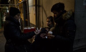 Una vecina voluntaria reparte café a una familia de solicitantes de asilo procedentes de Venezuela en las puertas del Samur Social de Madrid.- JAIRO VARGAS