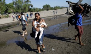 Migrantes de la caravana que viaja a Estados Unidos cruzando a la orilla guatemalteca del río en Ciudad Hidalgo, México. / Reuters