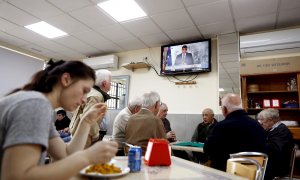 12/03/2020.- Un grupo de ancianos juega a las cartas este jueves en un bar del barrio de Aluche, en Madrid, mientras en la televisión comparece el presidente del Gobierno por el coronavirus. / EFE - MARISCAL