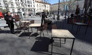 Varias personas recogen este viernes la terraza de un bar en la Plaza de Santa Ana, en el centro de Madrid. - EFE