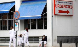 Personal sanitario del Hospital Arnau de Vilanova descansa unos minutos ante la puerta de urgencias, hoy durante el sexto día del estado de alarma decretado por el Gobierno.EFE/ Manuel Bruque