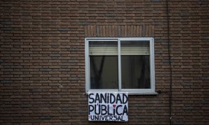 Un cartel en el que pone "Sanidad pública y universal" cuelga de una ventana durante la cuarentena / JAIRO VARGAS