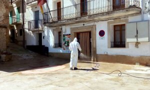 Pla general d'un operari de la Diputació de Tarragona desinfectant la plaça major de Paüls, a les portes de l'Ajuntament. ACN.