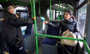 Un policía entrega una mascarilla a la pasajera de un autobús este lunes en Vigo. | EFE