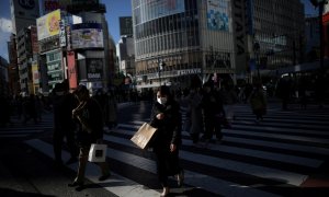 Una mujer con mascarilla cruza la calle  en el barrio de Shibuya, la principal zona comercial de Tokio. REUTERS/Stoyan Nenov