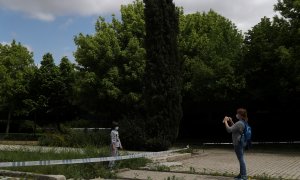 Una mujer realiza una foto a su hija en un parque clausurado de Madrid./ REUTERS