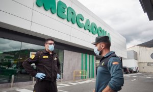 Un vigilante jurado y un guardia civil, ambos con mascarillas, delante de una tienda de Mercadona en Pamplona. E.P./Eduardo Sanz