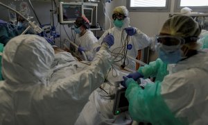 Personal sanitario totalmente protegido atiende a un paciente ingresado en la Unidad de Cuidados Intensivos del Hospital Infanta Sofía en San Sebastián de los Reyes (Madrid). Europa Press / Eduardo Parra