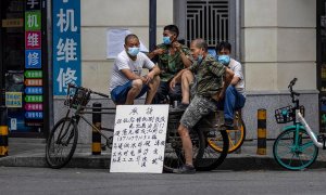 Varios obreros de la construcción aguardan en la calle junto a un cartel en el que ofrecen sus servicios en Cantón (China) / EFE