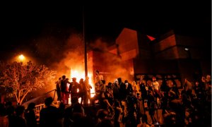 Los manifestantes se reúnen tras prender fuego a la entrada de una estación de policía mientras continúan las manifestaciones por George Floyd. REUTERS / Carlos Barria