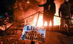 Los manifestantes aplauden mientras el fuego arde fuera del recinto policial de Minneapolis durante las protestas por la muerte de George Floyd. EFE / CRAIG LASSIG