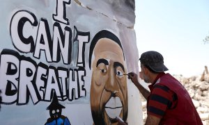 Un hombre sirio última un grafiti en homenaje a George Floyd en las ruinas de una casa en Idlib (Siria)./ EFE/EPA/YEHYA NEMAH