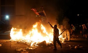 Un manifestante sostiene una bandera estadounidense quemada durante una protesta por George Floyd, en St. Louis, Missouri. REUTERS / Lawrence Bryant