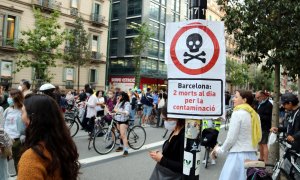 Primer pla d'un cartell que diu que la contaminació mata amb una manifestació contra els cotxes darrere, al centre de Barcelona. ACN / Pol Solà