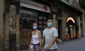 Una parella passa per davant d'una oficina de turisme tancada, a Barcelona. LAIA ROS